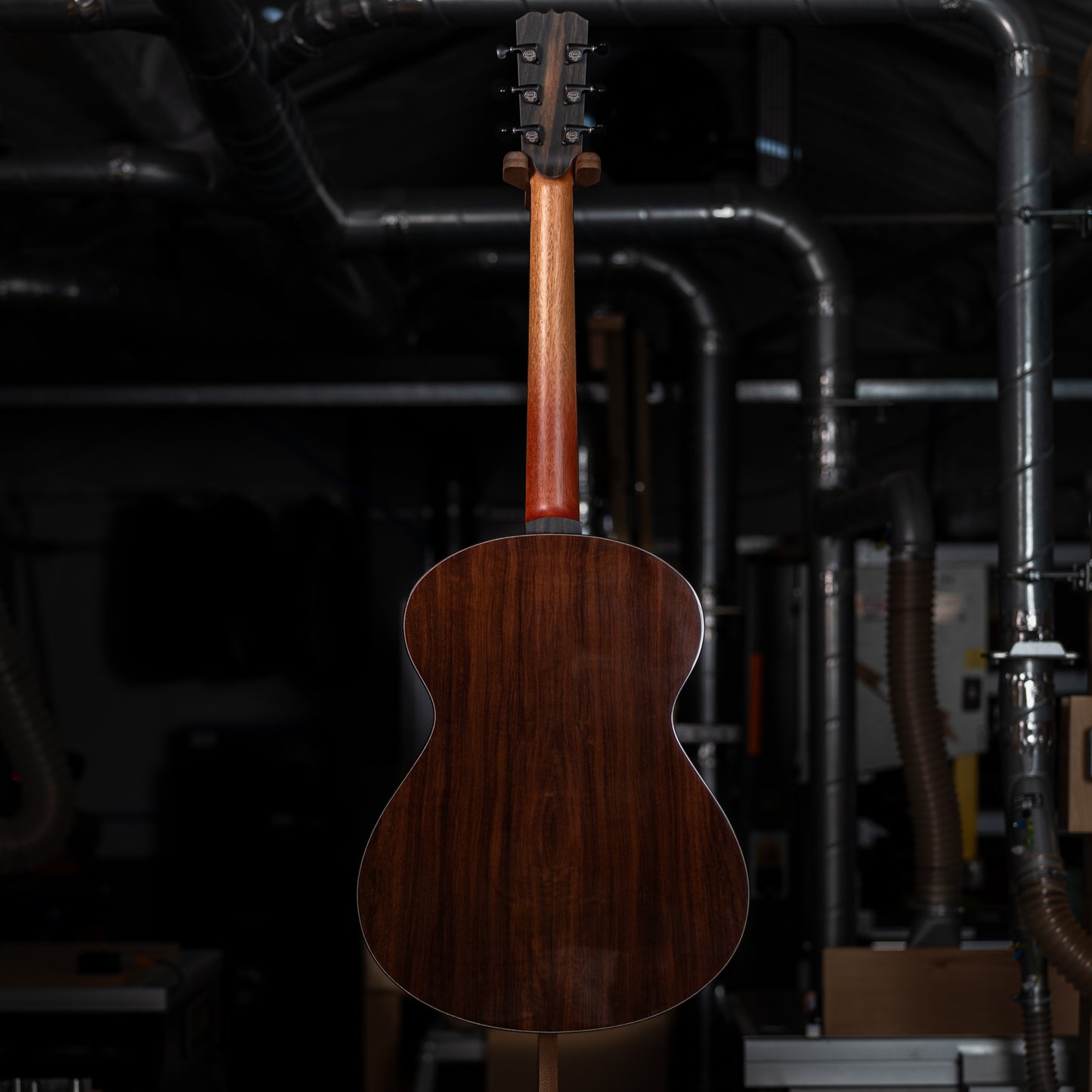 Wooden guitar on a stand with a dark, industrial background