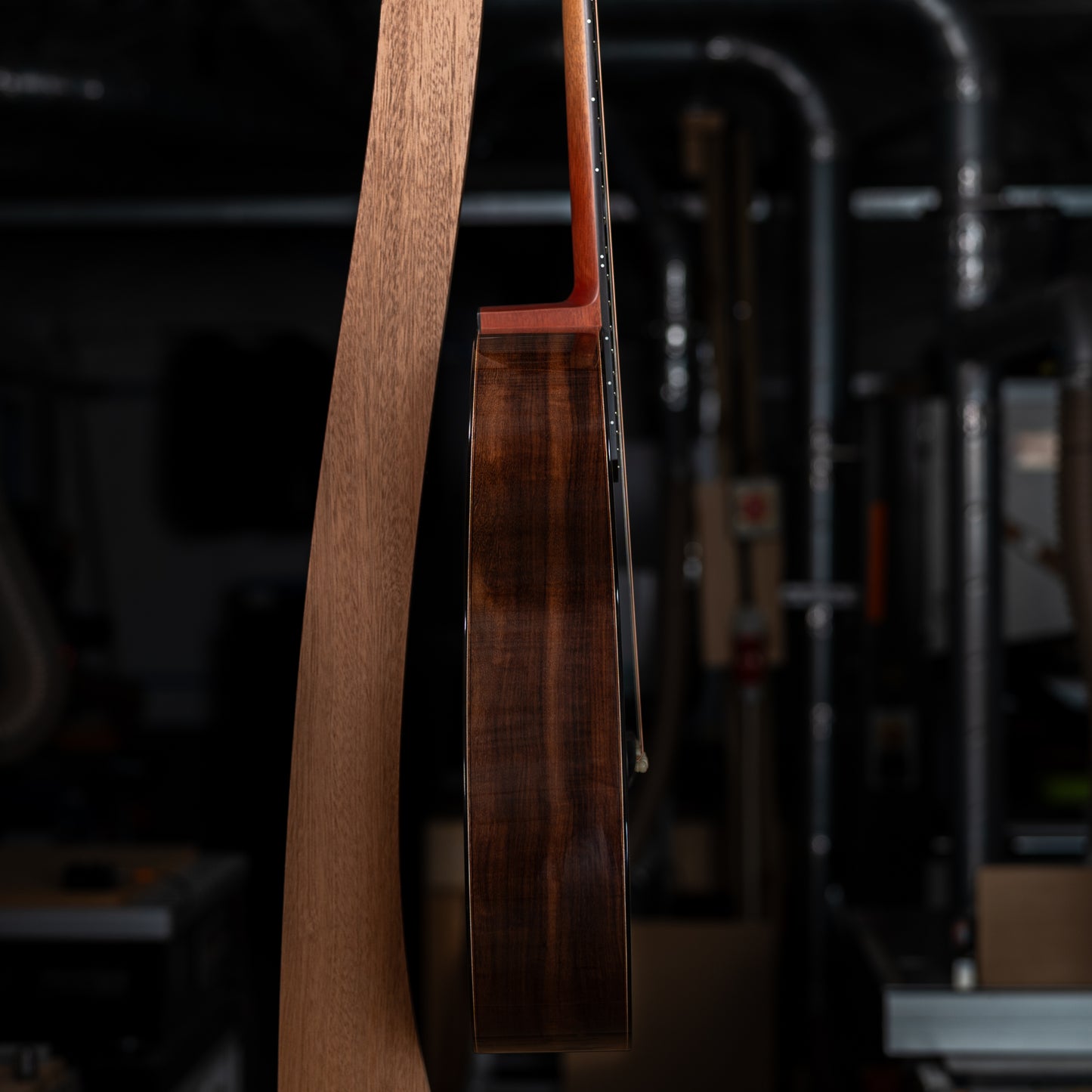 Close-up of the side of a guitar hanging in a guitar stand.