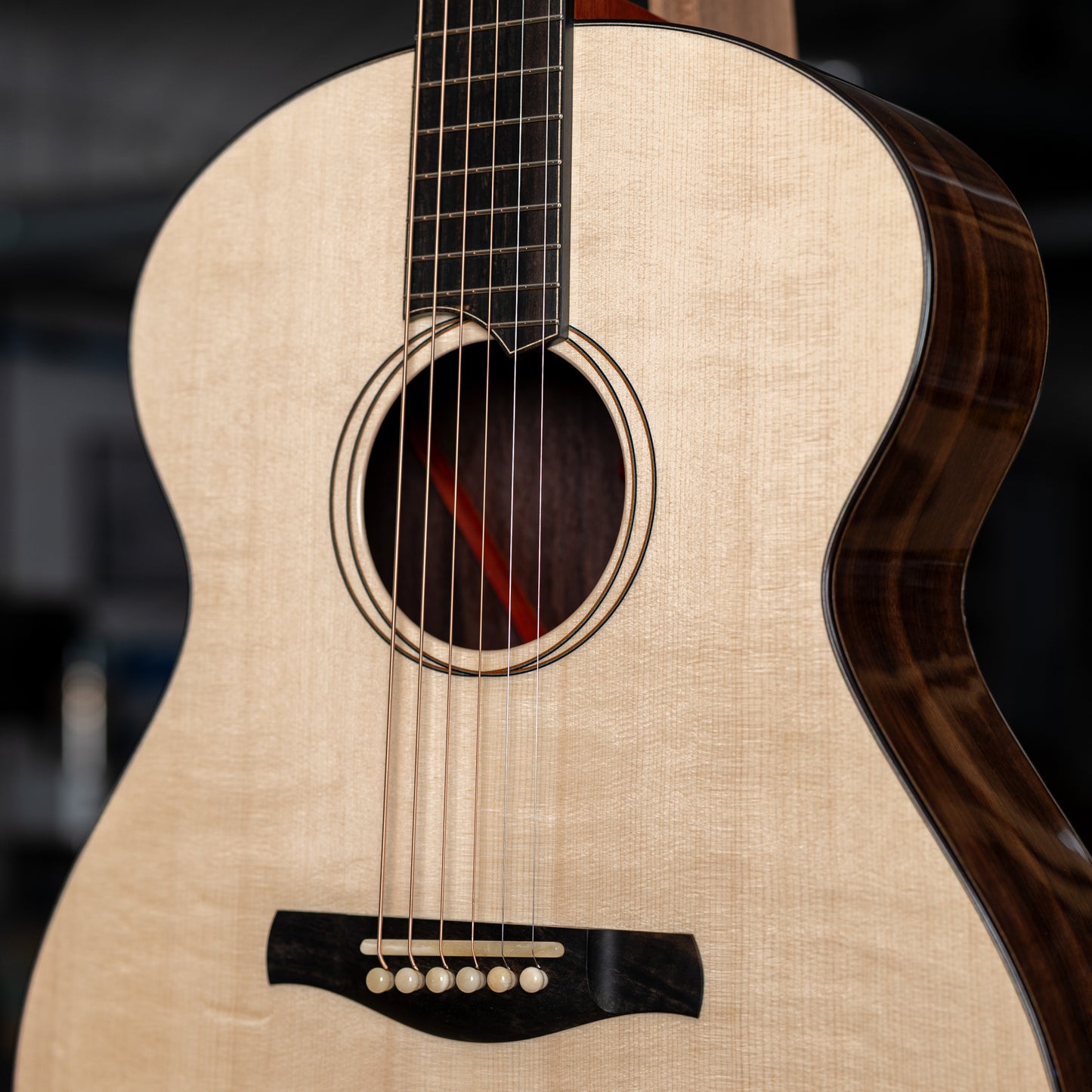 Close-up of an acoustic guitar with a dark brown finish on a blurred background