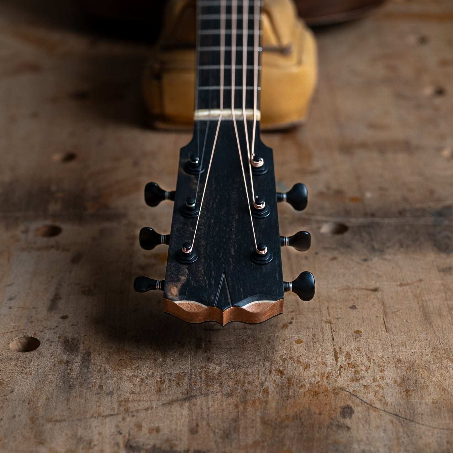 Close-up of a guitar's headstock on a wooden surface