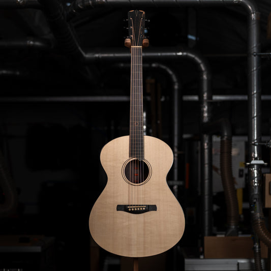 Photo of entire guitar from the front with a dark industrial workshop background