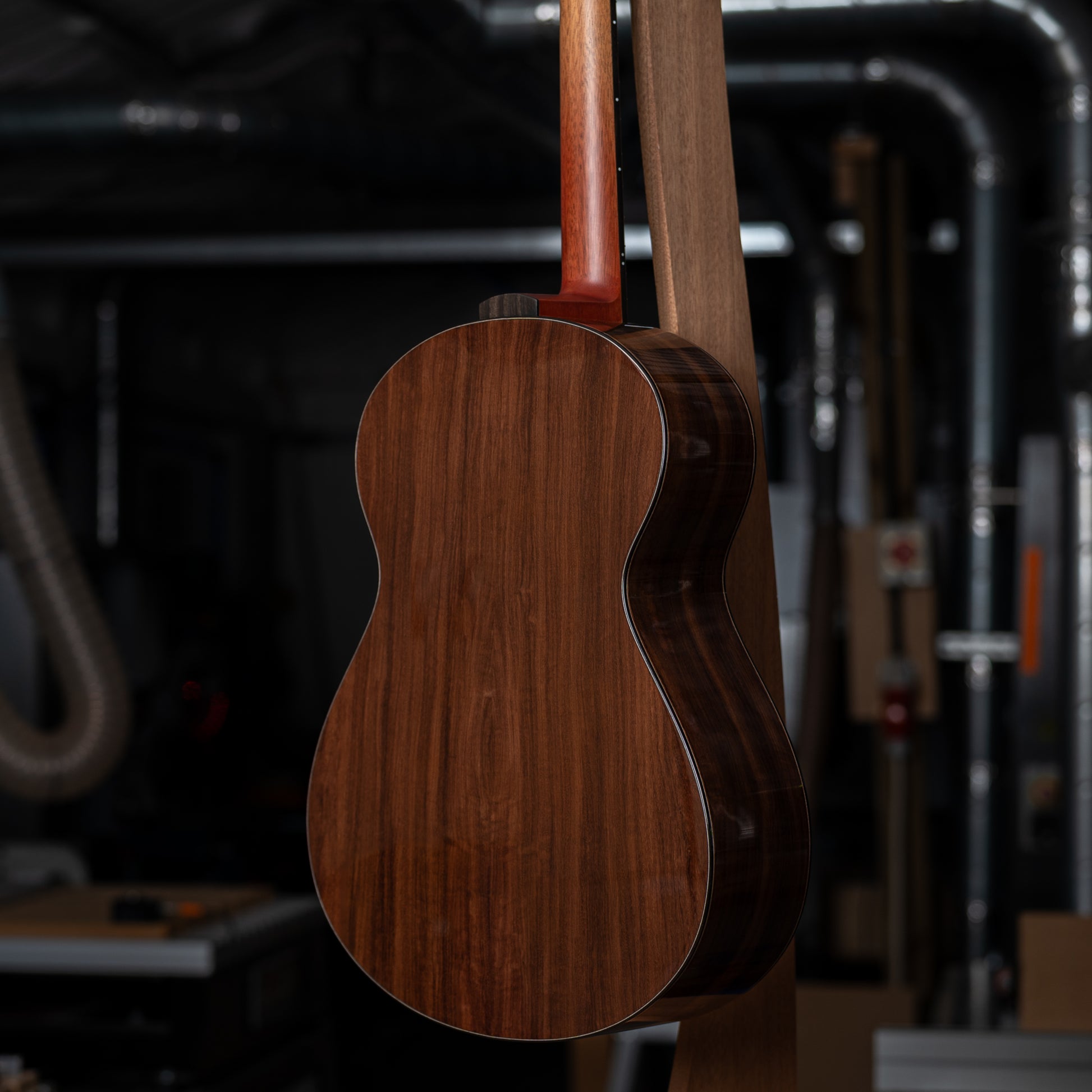 Back view of a wooden acoustic guitar in a workshop setting