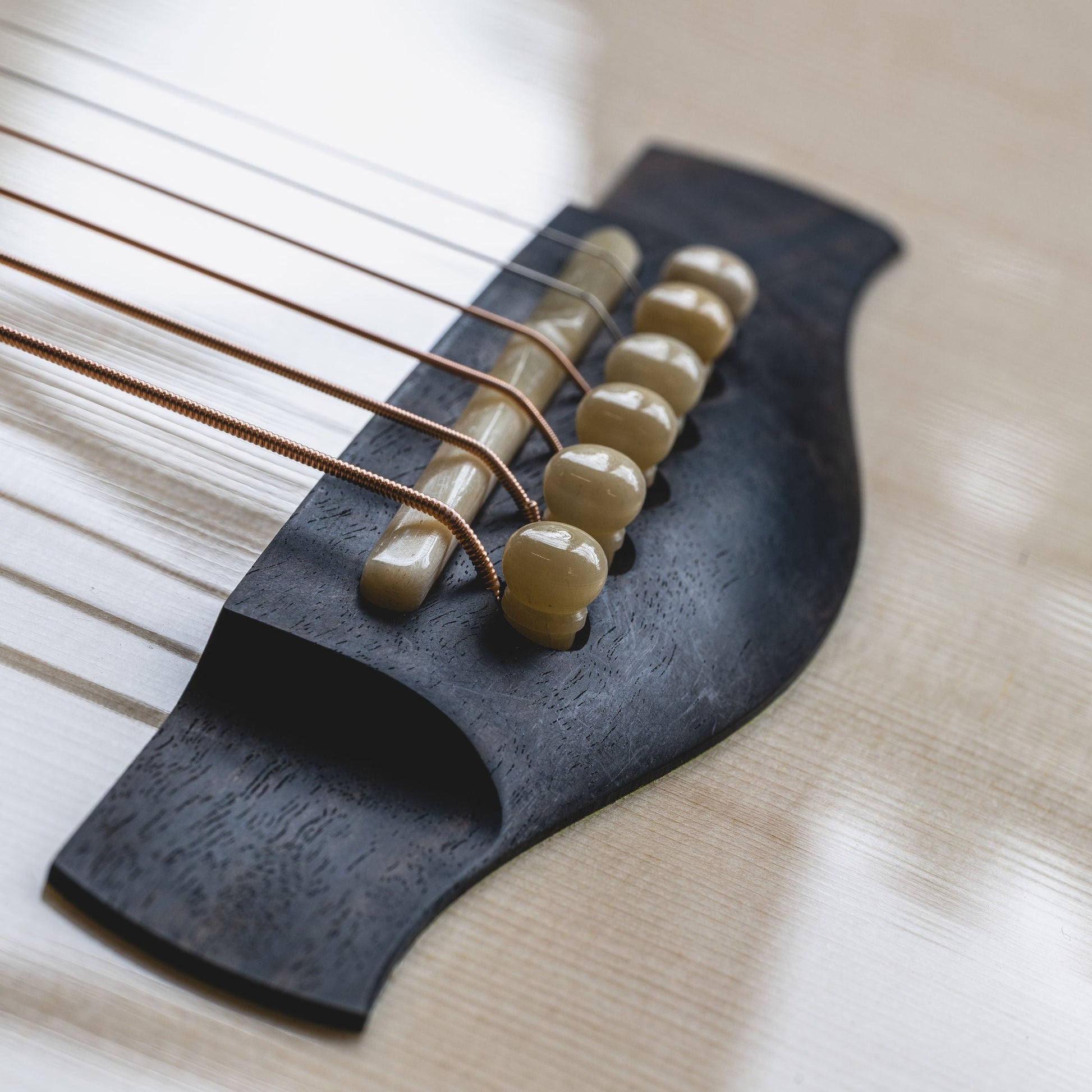 Close-up of a guitar's bridge and saddle with saddle pins and strings